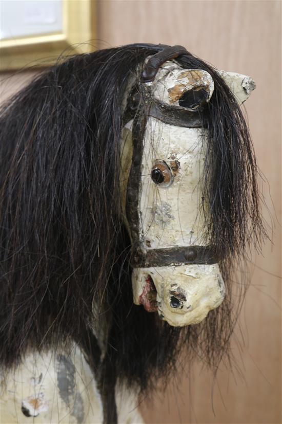 A Victorian painted carved wood rocking horse, with brass studded leather saddle, in trestle frame H.87cm